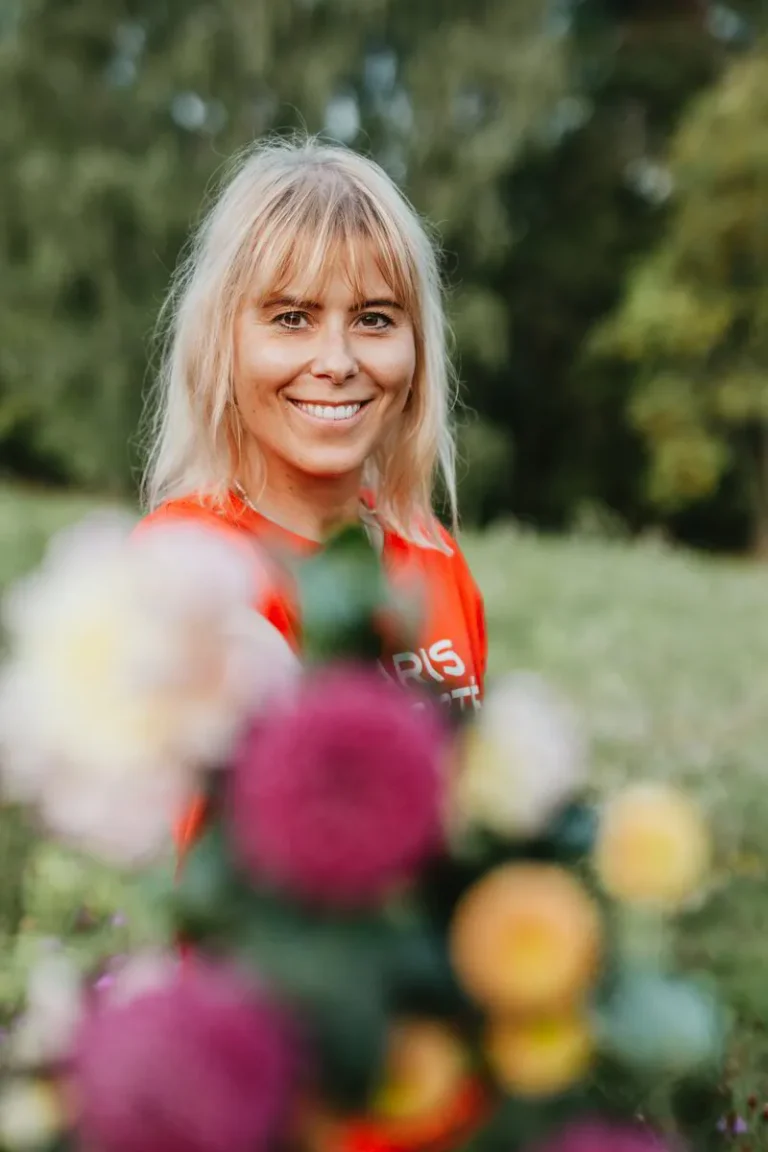 Lotta, coach, ler mot kameran i en grönskande utomhusmiljö, iklädd en röd tröja. Hon anlitade Karin Bergman för att skapa en professionell hemsida för sin coachingverksamhet.